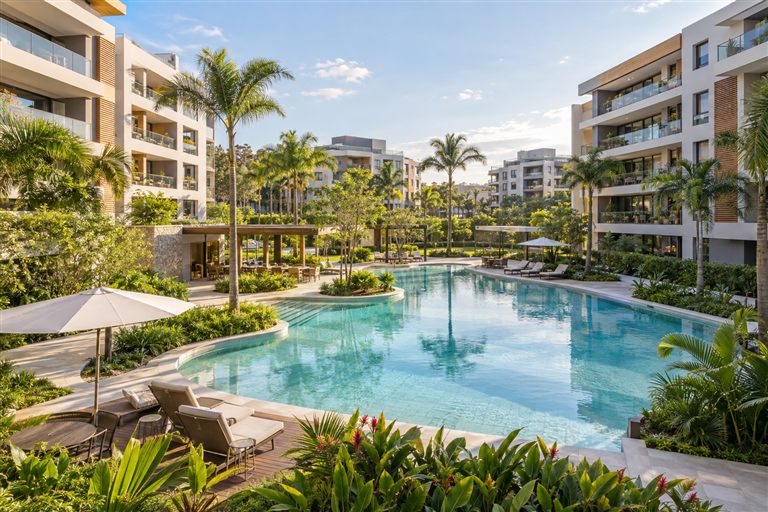 Piscina e espaços de lazer de um condomínio com jardins.